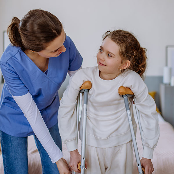 Young nurse helping to walk to little girl with a broken leg.